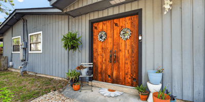 Inviting rear entryway featuring distinctive double doors and vibrant planters, perfect for welcoming guests home.