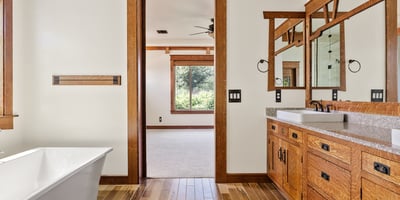 Spa inspired bathroom featuring a dual vanity, natural wood cabinetry, quartz counters, and modern fixtures. A luxurious and functional primary bath in this Phoenix residence.
