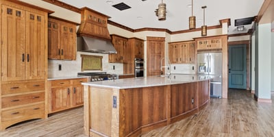 Gourmet kitchen featuring an oversized island, custom wood cabinetry, stone countertops, and professional-grade appliances. A standout space for cooking and entertaining.