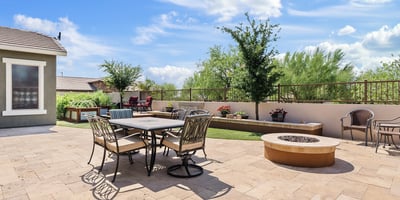 Enjoy cool evenings by the fire in this thoughtfully designed backyard oasis with lush greenery, raised planters, and a stylish built-in fire feature.