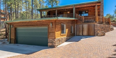 Eye-catching exterior featuring log siding, stone details, and a spacious driveway leading to a three-car garage. A welcoming first impression with timeless craftsmanship.