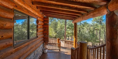 Shaded deck with log construction and wooded views, providing a quiet retreat surrounded by nature.
