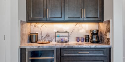 Built-in coffee and beverage bar with wine fridge and marble backsplash provides convenience and style in the kitchen area.