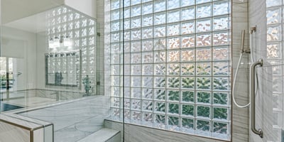 The walk-in shower includes a built-in bench and lighted niche, blending comfort with stylish upgrades.