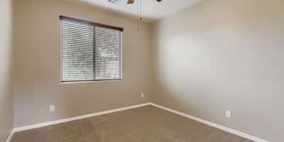 Flexible third bedroom with neutral tones and natural light ideal for children, office space, or guests.