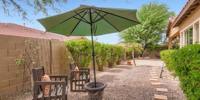Enjoy the tranquility of a private backyard with shaded areas, mature trees, and low-maintenance desert landscaping.