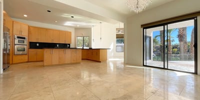 Bright kitchen-dining area with elegant tile floors, crystal lighting, and sliding doors opening to waterfront views ideal for entertaining in style.