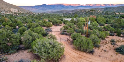 The rustic dual gate sets a charming tone, framed by sweeping mountains and desert foliage. It creates a secure, welcoming transition into this expansive Hackberry property.