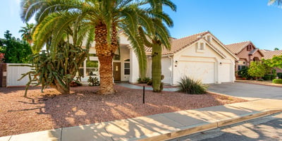 Beautifully landscaped Scottsdale front yard featuring mature palms, cactus accents, and low-maintenance gravel landscaping. This desert-inspired design complements the home's architecture while enhancing curb appeal.