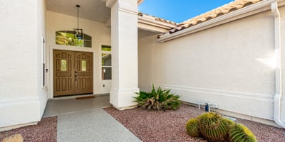 Inviting covered entry with double front doors, architectural details, and desert landscaping accents. The shaded Scottsdale entrance creates a warm and stylish arrival experience for guests and homeowners.