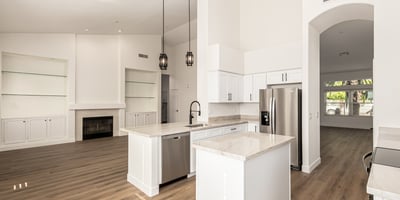 Open Scottsdale interior connecting the kitchen and living room with vaulted ceilings and modern flooring throughout. Built-in shelving and a fireplace create a warm focal point for everyday living.