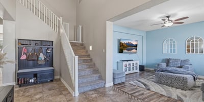 Welcoming entry foyer with soaring ceilings, tile flooring, and staircase leading to the loft and upper living areas of this spacious Queen Creek home.