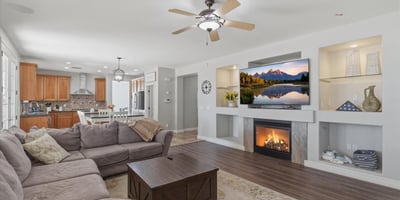 Stylish living area featuring a fireplace with decorative niches, ceiling fans, and durable wood-style flooring throughout the main living space.
