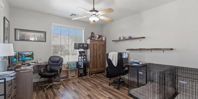 Spacious office area with wood-style flooring and large window, ideal for remote work, study, or a hobby room within this Queen Creek home.