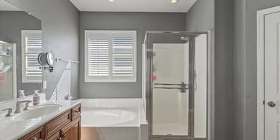 Spacious primary bathroom featuring a soaking tub, separate glass shower, and tile flooring designed for comfort and convenience.