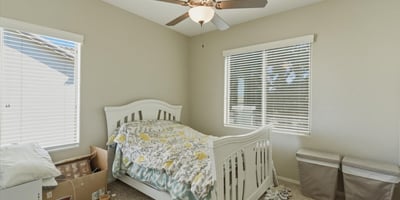 Comfortable secondary bedroom with plush carpet, ceiling fan, and large windows that bring in natural light, creating a welcoming space for guests or family.
