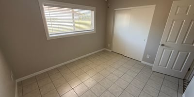 Light-filled bedroom featuring tile flooring, neutral walls, and ceiling fan lighting. The open layout makes the space perfect for guests, family members, or a home office.