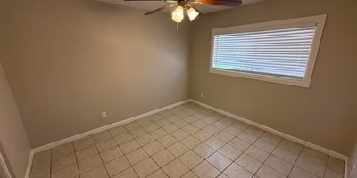 Bedroom with tile floors, ceiling fan, and soft neutral tones creating a relaxing environment. The space offers flexibility for a variety of bedroom or workspace uses.