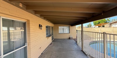 Covered patio space overlooking the fenced backyard pool area. The shaded outdoor living space is perfect for relaxing evenings or entertaining guests.
