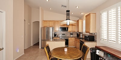 Open-concept kitchen and dining space with granite counters and plantation shutters. This Phoenix home is designed for easy entertaining and daily living.