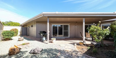 Private backyard with covered patio, desert landscaping, and outdoor seating areas ideal for relaxing or entertaining in Sun City.
