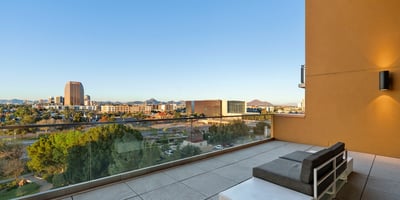 Spacious balcony with modern seating and glass railing, offering beautiful city and park views in Phoenix.