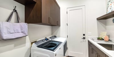 Efficient laundry space with built-in cabinets, sink, and modern washer and dryer, adding practicality to this Phoenix residence.