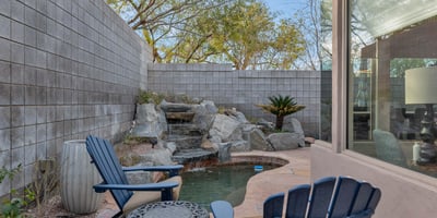 Serene backyard featuring a cascading water feature, patio seating, and low-maintenance landscaping in this Phoenix home.