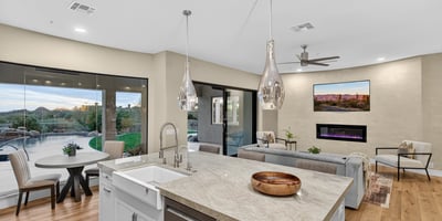 Spacious kitchen island with farmhouse sink and pendant lighting, overlooking the Scottsdale backyard with pool and lush landscaping.