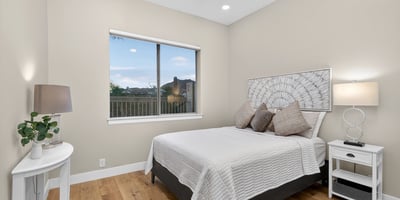 Bright Scottsdale bedroom with large window, wood flooring, and neutral finishes, offering a welcoming and versatile guest space.