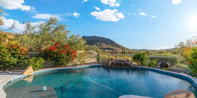 Scottsdale pool with rock waterfall feature, desert landscaping, and mountain views, offering a serene and private outdoor setting.