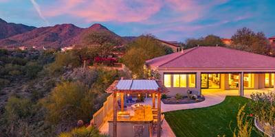 Scottsdale outdoor living space with covered patio, lawn, and outdoor kitchen, complemented by scenic mountain views.