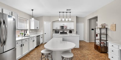 Functional kitchen with breakfast bar, white cabinets, and modern appliances. Seamless connection to living areas enhances flow in this Casa Grande home.