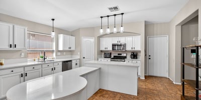 Bright open kitchen with large island, white cabinetry, and modern lighting. Perfect for entertaining and daily living in this Casa Grande home.