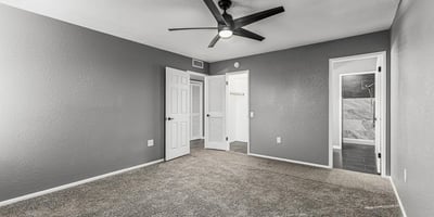Comfortable primary bedroom with soft carpet, ceiling fan, and neutral palette. This Sun City home includes updated features and easy access to a renovated bathroom.