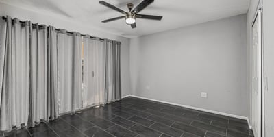 Bright bedroom with tile flooring, ceiling fan, and natural light. This Sun City home offers updated finishes and flexible room options.