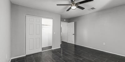 Bedroom with durable tile flooring, ceiling fan, and closet storage. This Sun City home features updated flooring and low-maintenance living.
