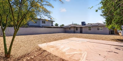 Private backyard with concrete pad and mature landscaping, offering versatile outdoor living potential in this Phoenix home.