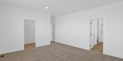 Comfortable primary suite featuring soft carpeting, generous dimensions, and easy access to the ensuite bath and walk-in closet. This inviting space offers a peaceful setting to unwind while enjoying the home's thoughtful layout.