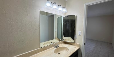 Well-designed primary bathroom featuring an oversized vanity, updated light fixtures, and abundant counter space. The functional layout provides comfort and convenience for daily routines.