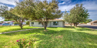 A spacious grassy front yard accented by mature shade trees creates a peaceful setting while highlighting the home's refreshed exterior and inviting design.