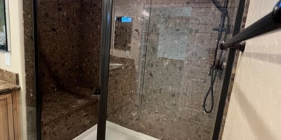 Luxurious walk-in shower with stylish tile surrounds, built-in bench seating, black framed glass enclosure, and upgraded shower fixtures creating a sophisticated spa-like experience.