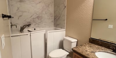 Well-appointed guest bathroom featuring a convenient walk-in tub, updated vanity, durable tile flooring, and attractive finishes that provide comfort, accessibility, and everyday functionality.
