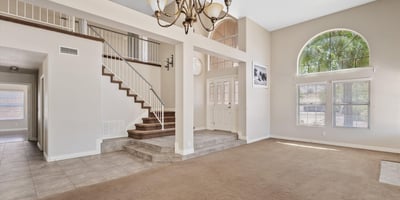 Architectural columns, dramatic ceiling heights, and an elegant staircase create a spacious, open feel throughout the main living area. The layout flows naturally into adjoining rooms for effortless entertaining.