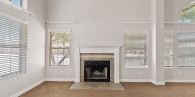 The wood-burning fireplace serves as the centerpiece of this spacious living room, complemented by tall ceilings and large windows that brighten the space. Its warm ambiance makes it the perfect place to gather with family and friends throughout the year.