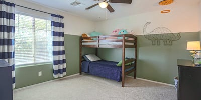 Large bedroom with plush carpeting, ceiling fan, and oversized window creating a bright, cheerful space. Perfect for children, guests, or a flexible bonus bedroom.