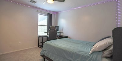 Spacious upstairs bedroom featuring plush carpeting, a ceiling fan, and an open layout with plenty of room for larger furnishings. A comfortable and flexible living space that complements this thoughtfully designed Waddell home.