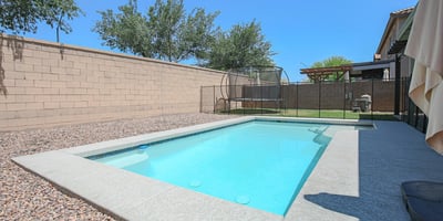 Attractive swimming pool with a baja shelf, surrounding patio, and secure fencing for added peace of mind. A standout feature that complements this beautiful Waddell home.