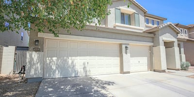 Charming front exterior showcasing a three-car garage, mature landscaping, and inviting covered entry. This attractive Waddell property offers excellent curb appeal and functional everyday convenience.
