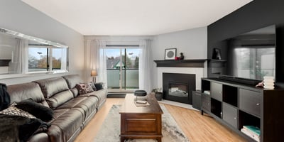 Spacious living area features modern decor, large windows for natural light, and a cozy fireplace.